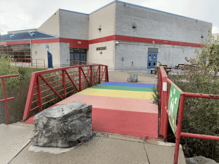 <b>Rainbow Bridge Leading to Building</b><br>This photo of a rainbow-colored bridge on Sheridan campus was taken with my phone. The bridge, originally built to span a small water feature, now also represents inclusivity and diversity. It leads towards student facilities and is a vibrant reminder of the welcoming environment at Sheridan.
