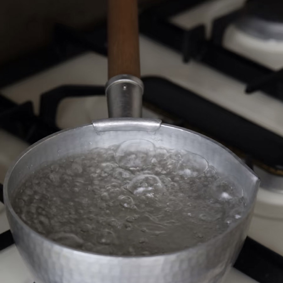 A pot of boiling water on a stove, visually representing the bubbling and popping sounds of a liquid reaching boiling point.