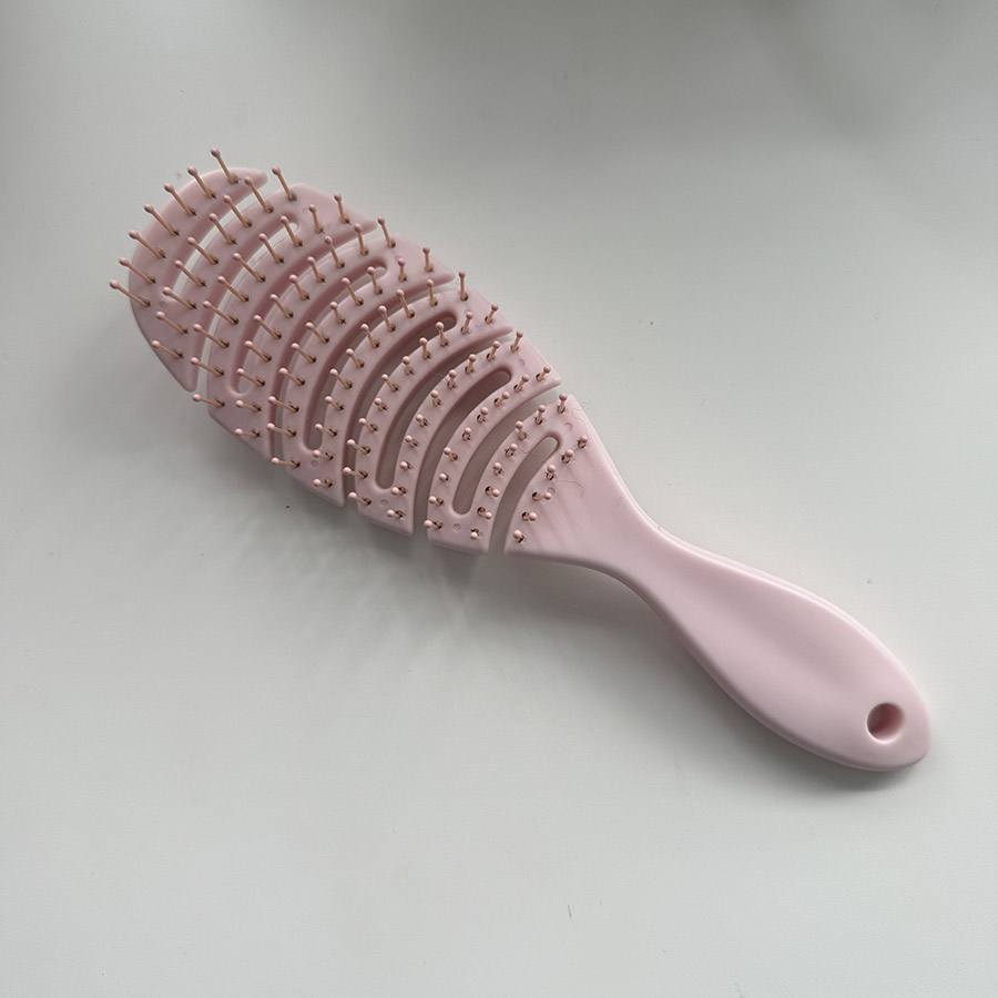 A pink hairbrush, showing the bristles passing through hair, associated with the sound of brushing.
