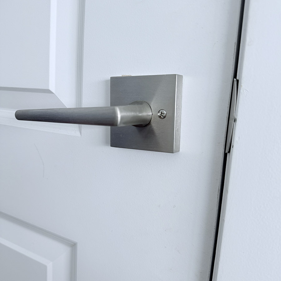A metal door handle in the act of being used, symbolizing the click and creak as the door opens or closes.