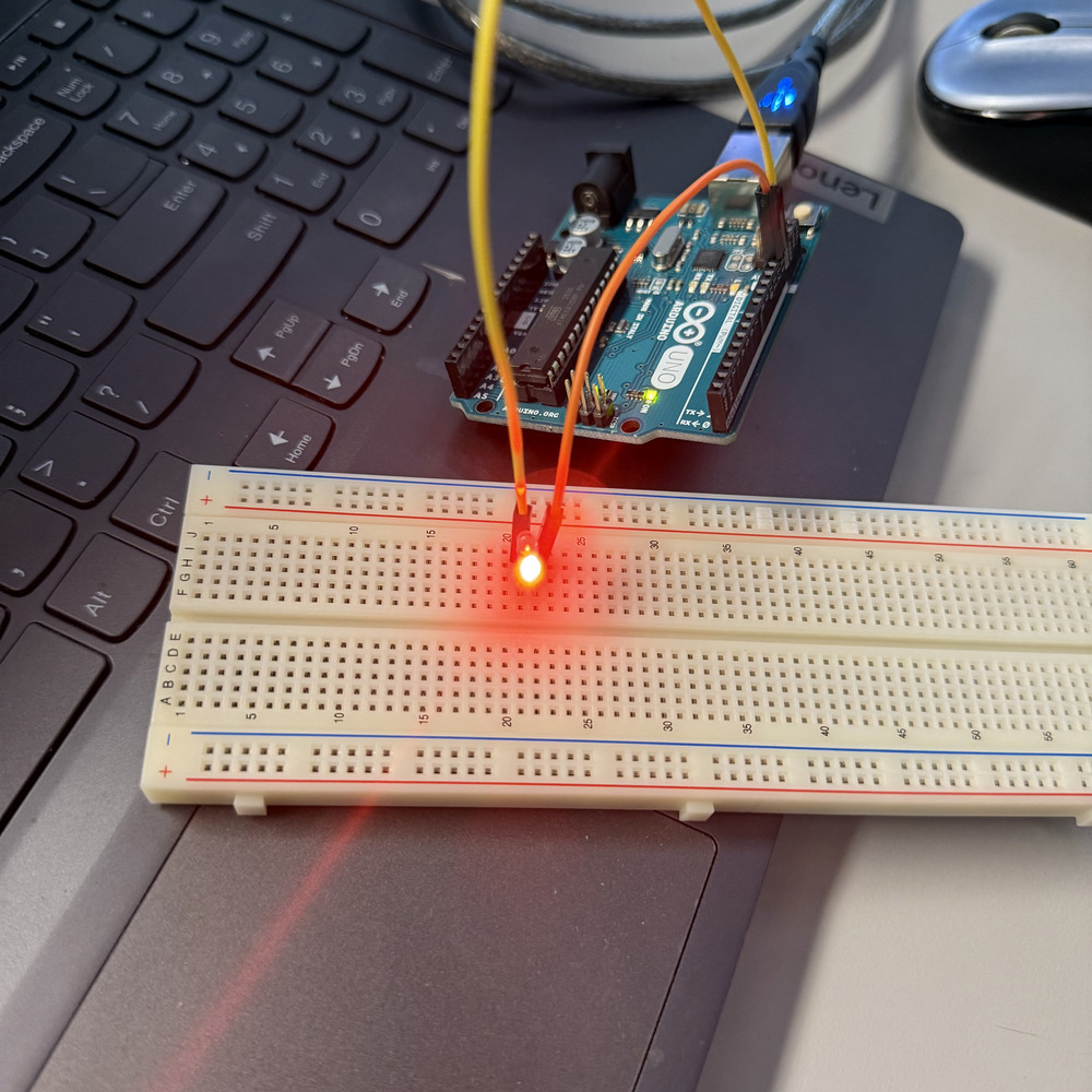 <b>Lighting up a red LED</b><br>I connected an LED to a breadboard and wired it to the Arduino. The red LED lights up, which means the circuit is complete and the code is working. This is my first successful test using digital output.