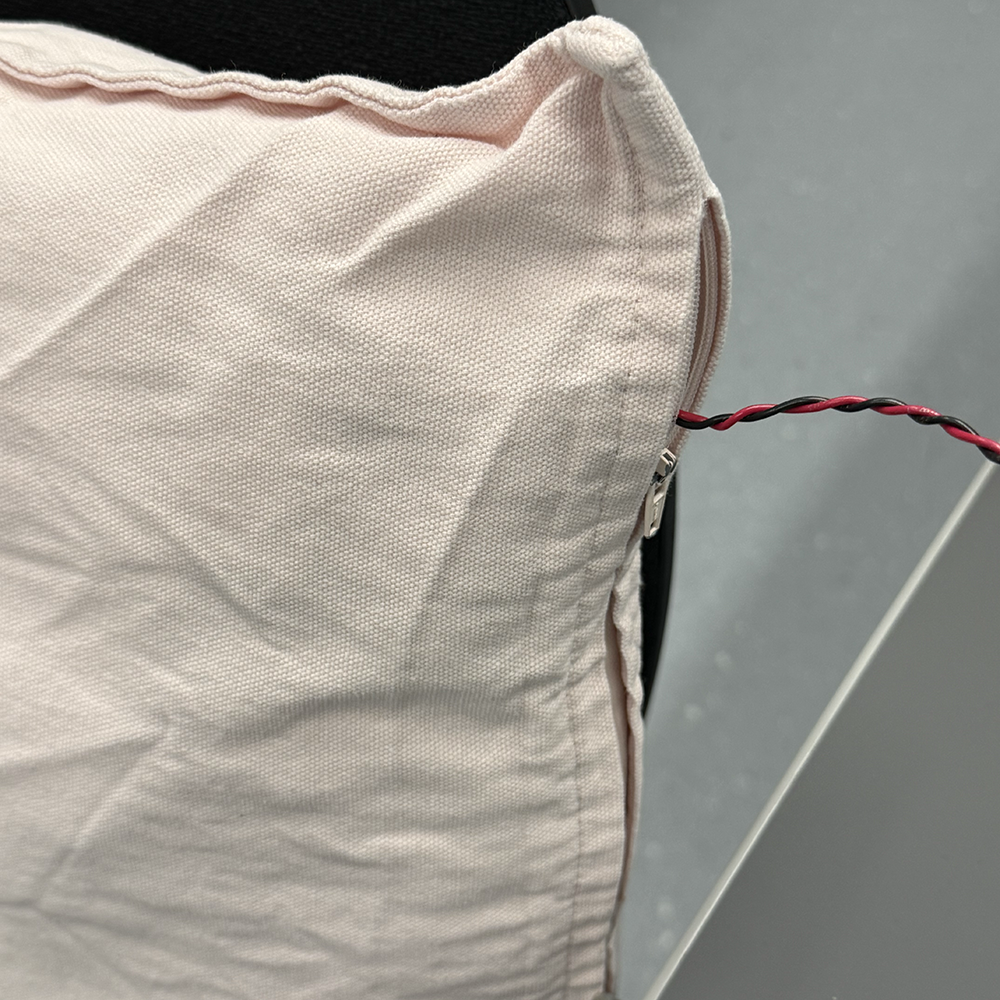<b>Placing the Sensor Inside the Cushion</b><br>We placed the force sensor inside the cushion and guided the wire through the side opening. This step made the cushion functional while keeping the sensor invisible, so the interaction stays soft and natural.